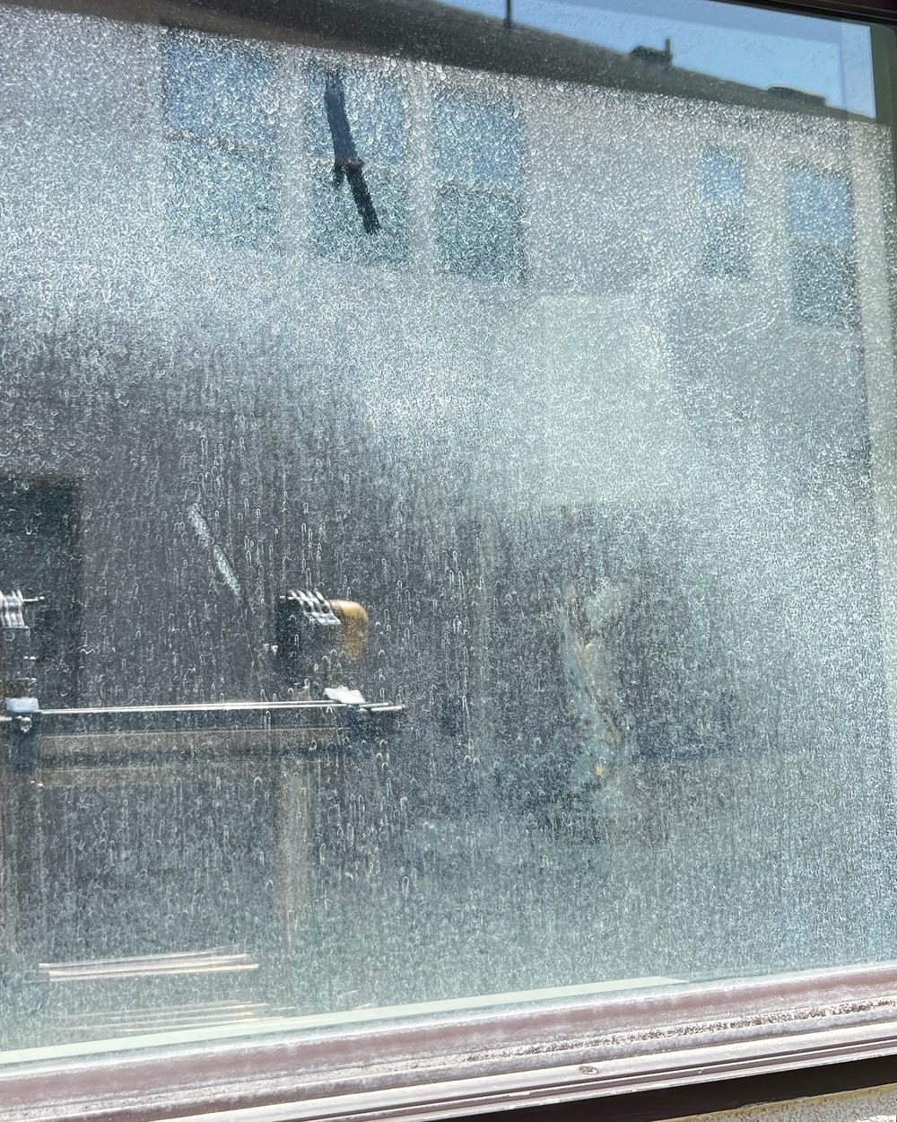 Before and after: hard-water stains removed from a window, Casa Care job (before photo)
