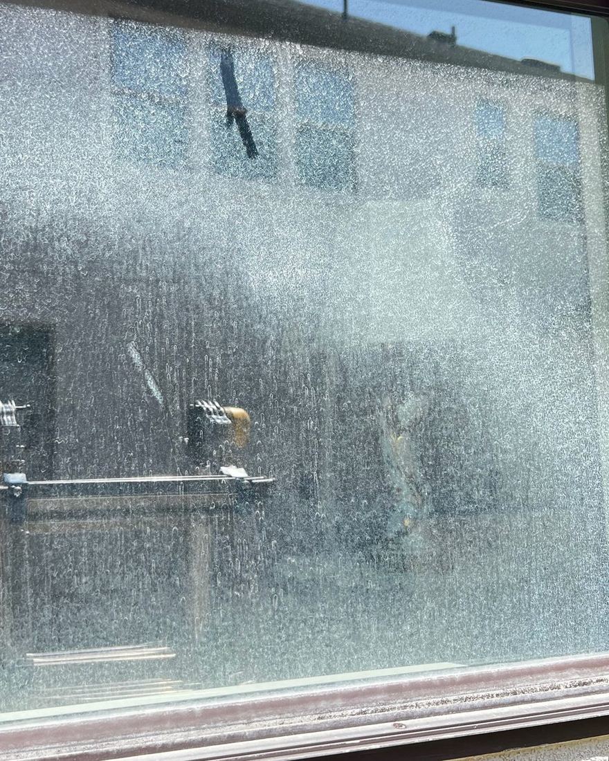 Before and after: hard-water stains removed from a window, Casa Care job (before photo)