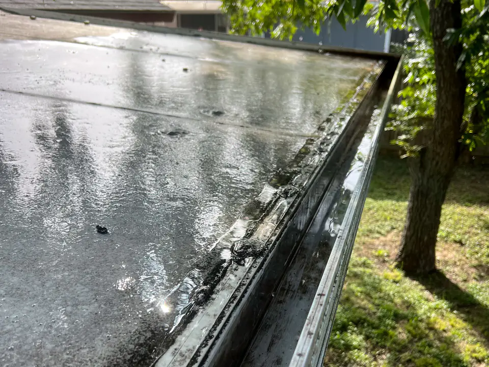 Clean, wet gutter along a flat roof edge after flushing on a Casa Care job